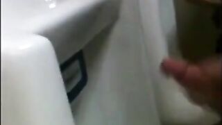 two slim dicks getting wanked at the urinals